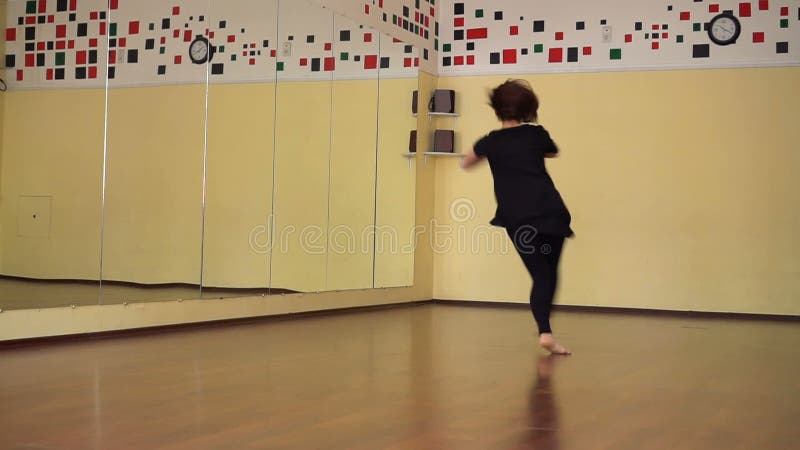 Ballerino moderno che riscalda in uno studio con gli specchi Ballo di formazione della ragazza