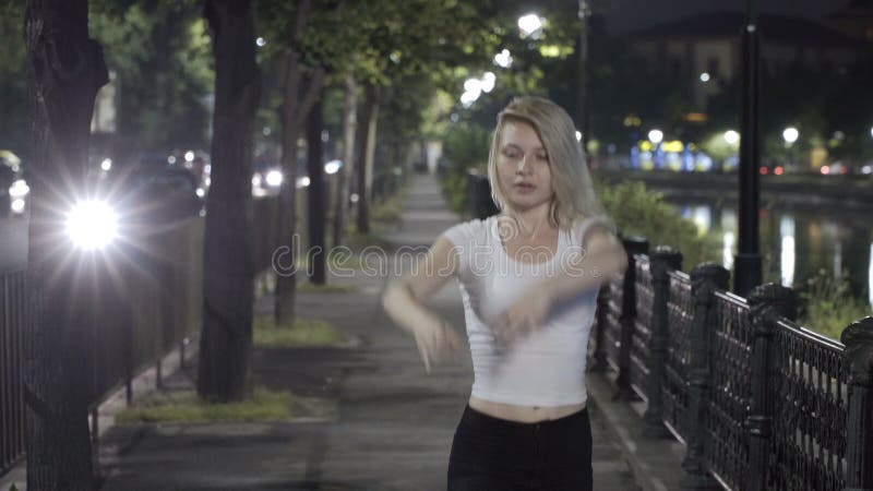 Ballet blond de danse de fille sur la rue la nuit exprimant la grâce et l'élégance