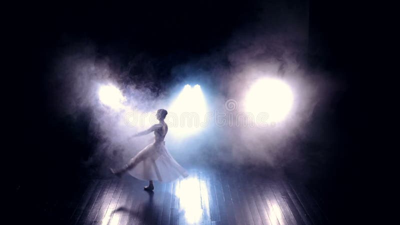 A ballet dancer makes high jumps through a dark stage.