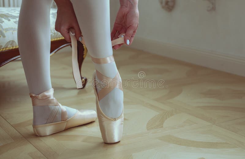 Ballet dancer tying ballet shoes. close-up.