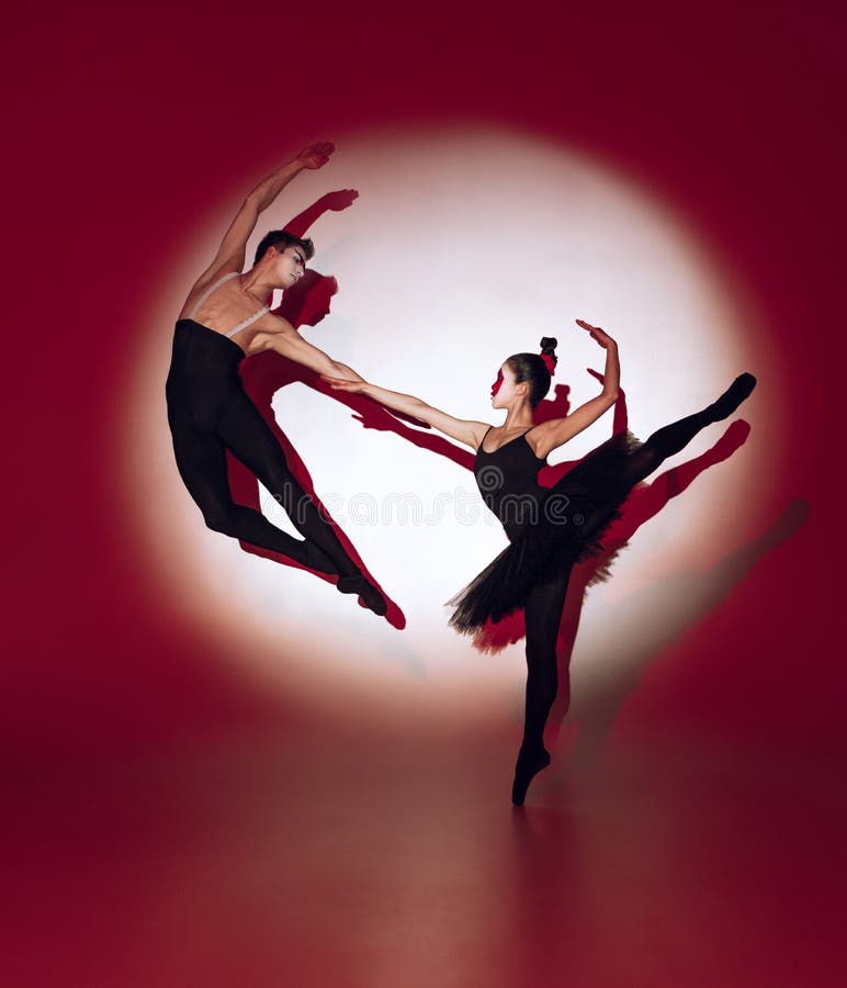 Ballet dancers dancing over red studio background. Modern design. Contemporary colorful conceptual light as rising sun