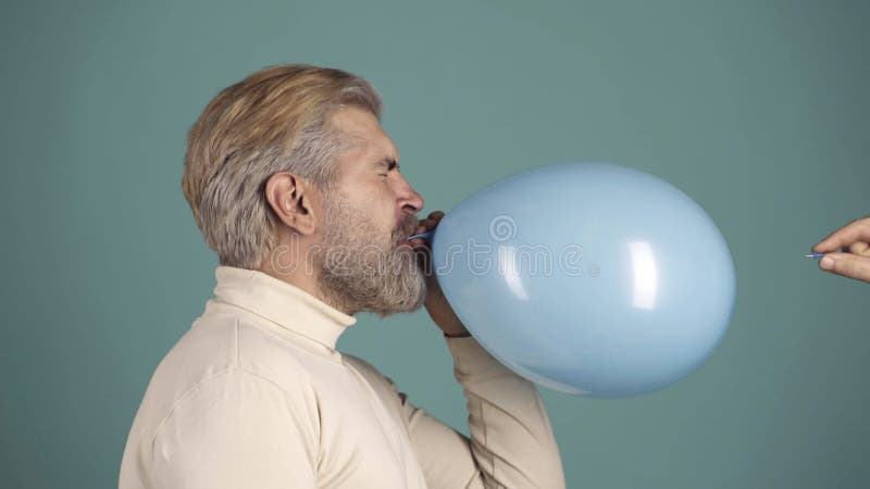 Ballonboom. grappige man die de naald over de luchtballon houdt een moment dat de luchtbel barst. geïsoleerd op blauw. gekke kerel