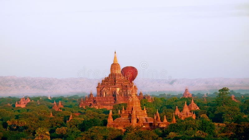 Ballonger för varm luft som flyger på soluppgång över forntida buddistiska tempel på Bagan myanmar