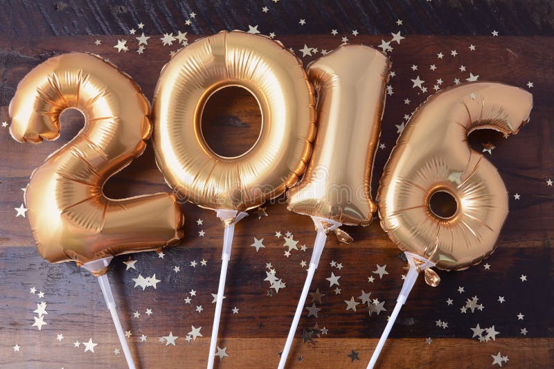 Happy 2016 gold New Year Balloons with glitter stars on dark wood table background. Happy 2016 gold New Year Balloons with glitter stars on dark wood table background.