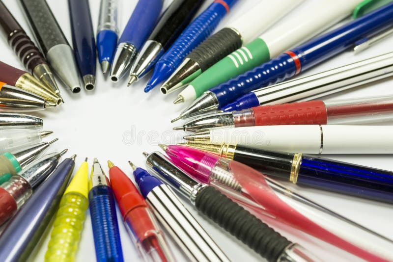 Ballpoint pens and mechanical pencils of various shapes and colors with their tip oriented inwards, forming a circle