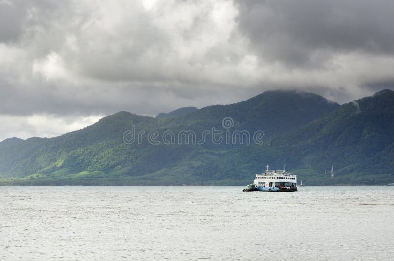 Balsa da carga no mar tropical sob nuvens pesadas da tempestade da monção e na ilha tropical de Koh Chang no horizonte em Tailând fotografia de stock royalty free Balsa da carga no mar tropical sob nuvens pesadas da tempestade da monção e na ilha tropical de Koh Chang no horizonte em Tailând fotografia de stock royalty free