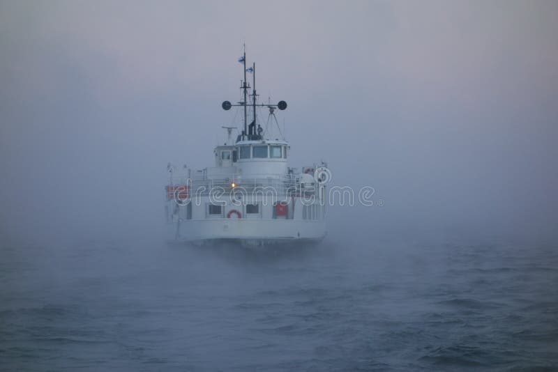 Ferry departing Suomenlinna fortress island on Baltic sea in midst of thick sea smoke or fog on extremely cold January morning at dawn in Helsinki, Finland on 5 January 2016. Ferry departing Suomenlinna fortress island on Baltic sea in midst of thick sea smoke or fog on extremely cold January morning at dawn in Helsinki, Finland on 5 January 2016.