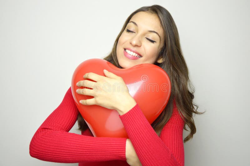 Balón de aire rojo del corazón del abrazo hermoso feliz de la muchacha en fondo gris Concepto del día del ` s de la tarjeta del d