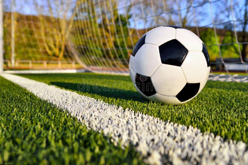 Football lying on the green soccer pitch behind the goal line. Football lying on the green soccer pitch behind the goal line