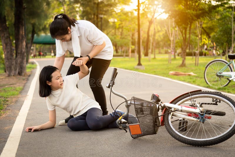 Bambina asiatica che si siede sulla strada con un dolore di gamba dovuto un incidente della bicicletta, la caduta della bici vici immagini stock libere da diritti Bambina asiatica che si siede sulla strada con un dolore di gamba dovuto un incidente della bicicletta, la caduta della bici vici immagini stock libere da diritti