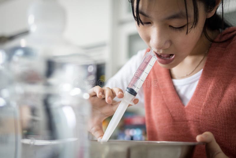 Asian child girl having stuffy nose,difficulty breathing,nasal wash,nose cleaning with syringe and saline,nasal sinus infection,dust allergic,rhinitis,nasal irrigation during common cold and influenza. Asian child girl having stuffy nose,difficulty breathing,nasal wash,nose cleaning with syringe and saline,nasal sinus infection,dust allergic,rhinitis,nasal irrigation during common cold and influenza