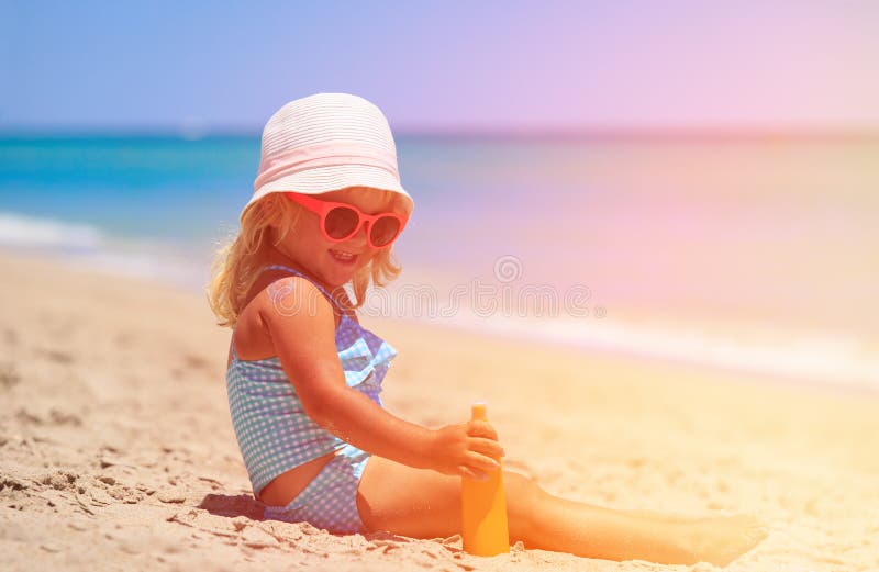 Bambina che applica la crema del sunblock sulla spalla immagine stock Bambina che applica la crema del sunblock sulla spalla immagine stock