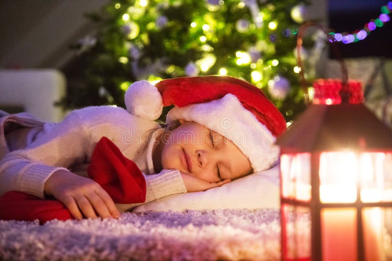 Bambina che dorme sotto l'albero di Natale fotografia stock Bambina che dorme sotto l'albero di Natale fotografia stock