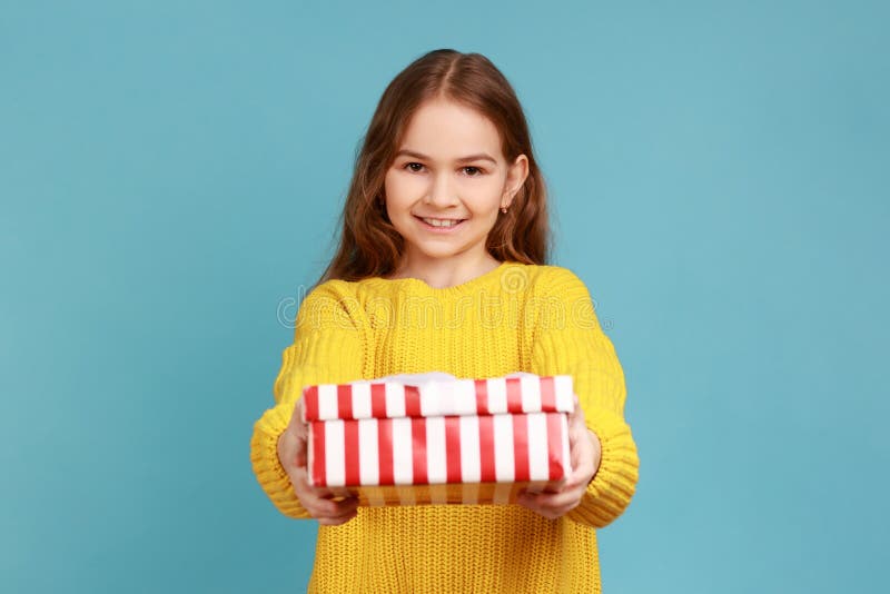 Bambina che fa un regalo in camera con un sorriso che saluta in vacanza e condivide il presente. immagine stock