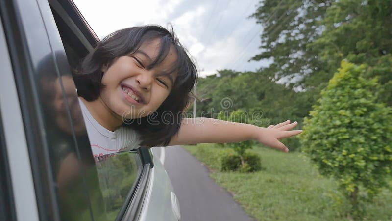 Bambina che gioca sull'automobile della finestra, famiglia che viaggia sulla campagna