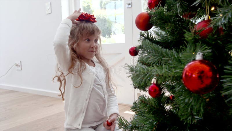 Bambina che gioca vicino all'albero di Natale a casa stock footage