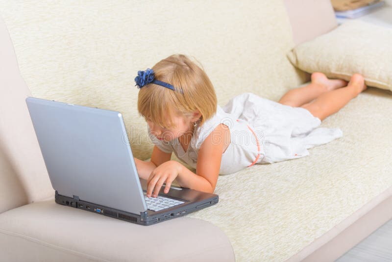Bambina che mette sullo strato con il computer portatile