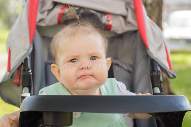 Bambina che si siede in una carrozzina immagine stock libera da diritti Bambina che si siede in una carrozzina immagine stock libera da diritti