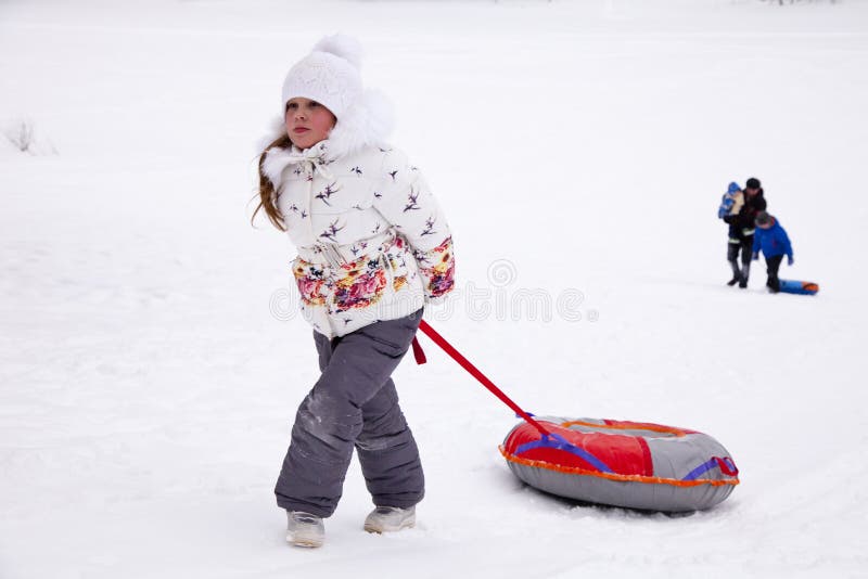 Bambina che tira la tubatura della neve della cinghia fotografia stock Bambina che tira la tubatura della neve della cinghia fotografia stock