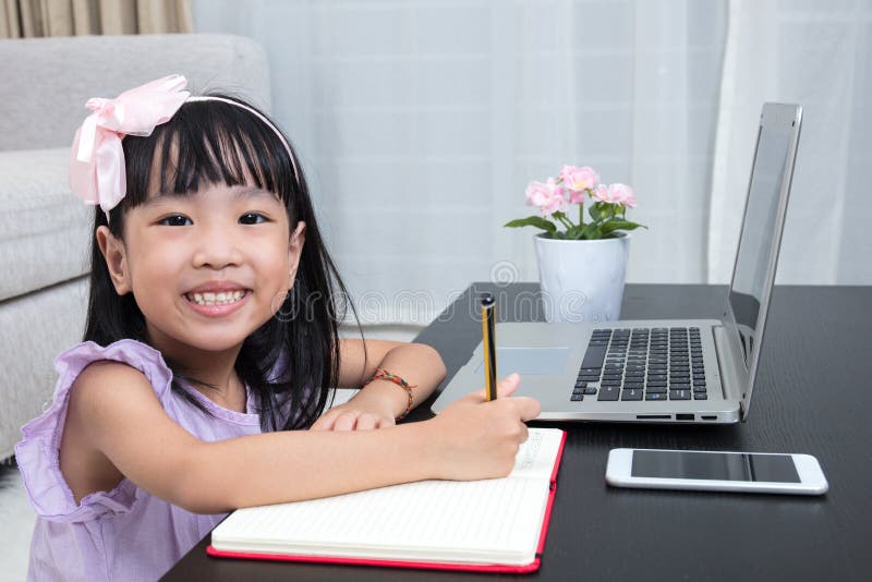 Bambina cinese asiatica che fa compito con il computer portatile