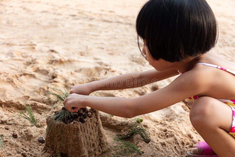 Bambina cinese asiatica che gioca sabbia alla spiaggia