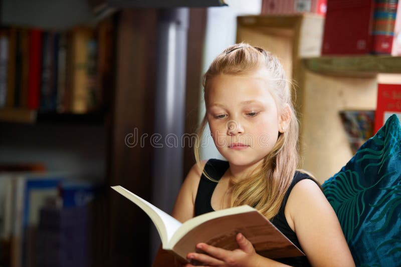 Bambina e biblioteca per leggere libri e imparare letteratura linguistica e narrativa sul divano. bambino immagini stock libere da diritti
