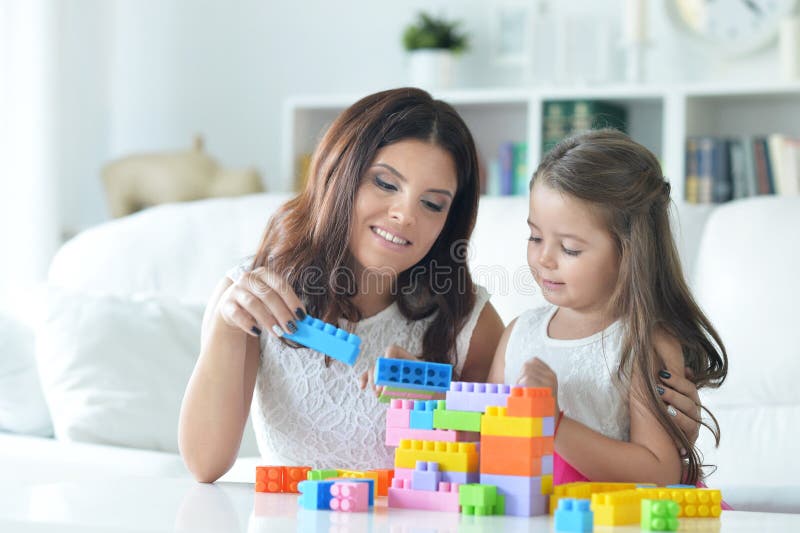 Bambina e sua madre che giocano con i blocchi di plastica variopinti fotografia stock libera da diritti