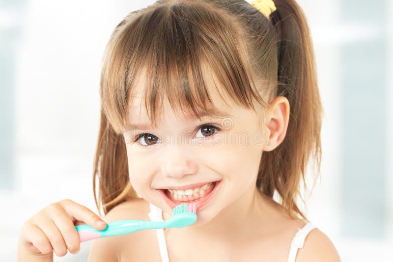 Bambina felice che pulisce i suoi denti fotografia stock libera da diritti