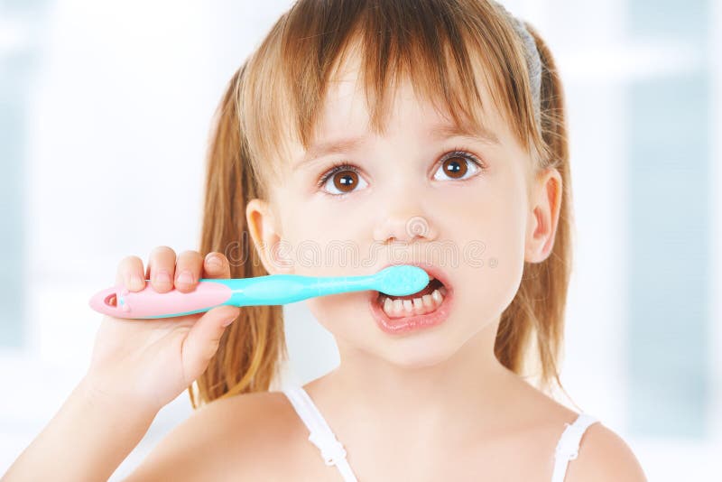 Bambina felice che pulisce i suoi denti fotografia stock