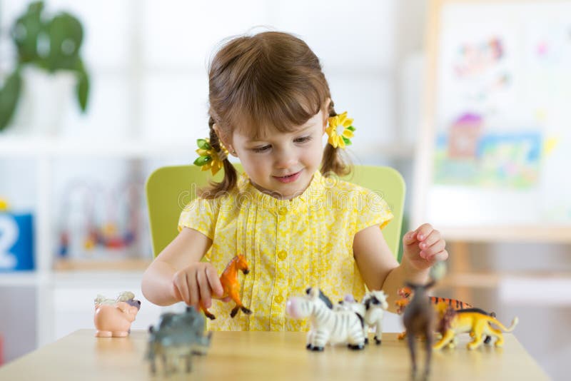 Bambina felice Il bambino sorridente del bambino gioca i giocattoli animali a casa o l'asilo immagine stock