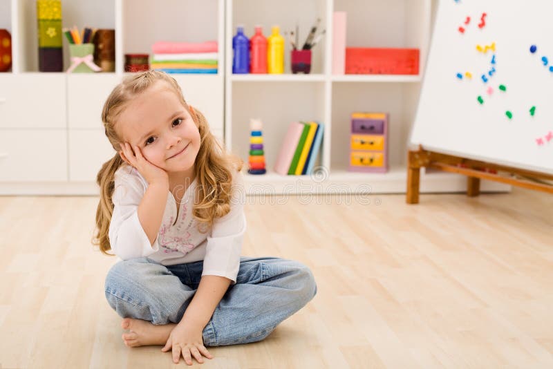 Bambina felice nella sua seduta della stanza fotografia stock libera da diritti