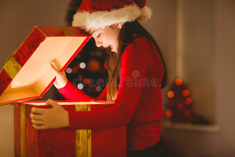 Bambina festiva che apre un regalo d'ardore di natale immagine stock libera da diritti Bambina festiva che apre un regalo d'ardore di natale immagine stock libera da diritti