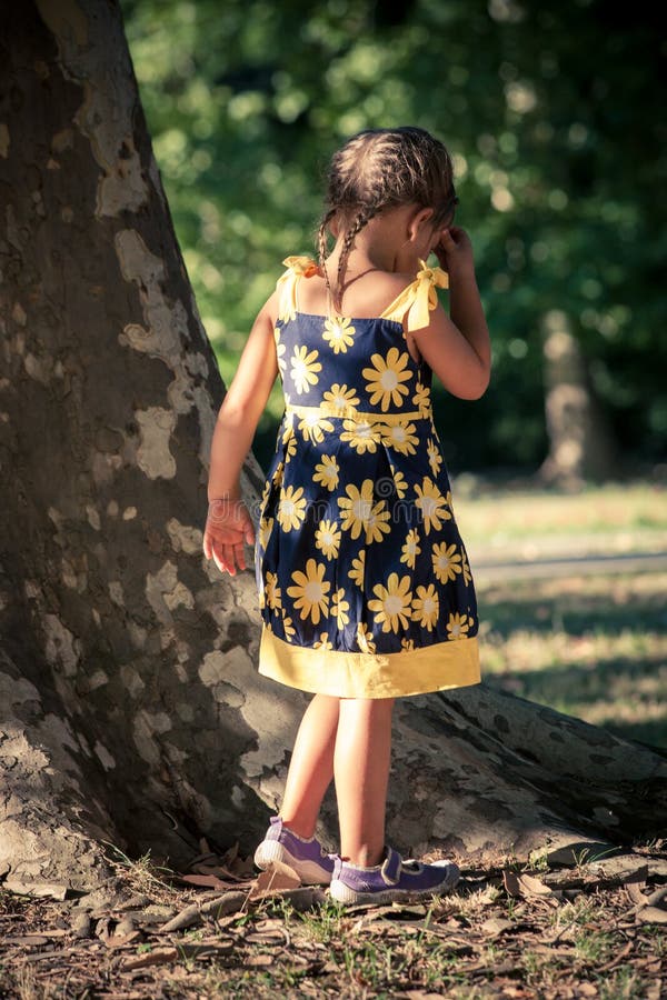 Bambina nella passeggiata sveglia del vestito da estate in parco dall'albero enorme immagini stock libere da diritti Bambina nella passeggiata sveglia del vestito da estate in parco dall'albero enorme immagini stock libere da diritti