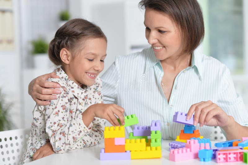 Bambina riccia ed il suo gioco della madre fotografia stock libera da diritti