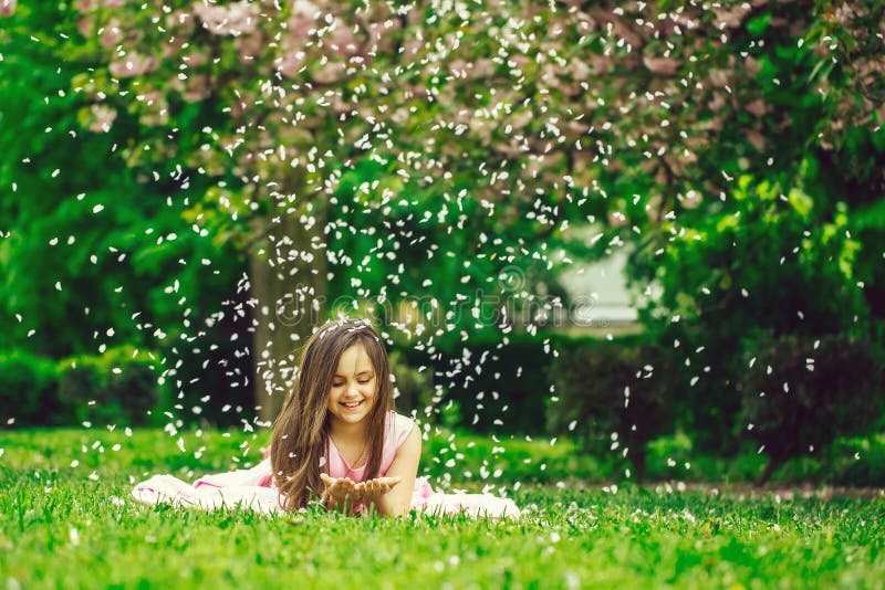Bambina su erba verde con i petali fotografie stock Bambina su erba verde con i petali fotografie stock