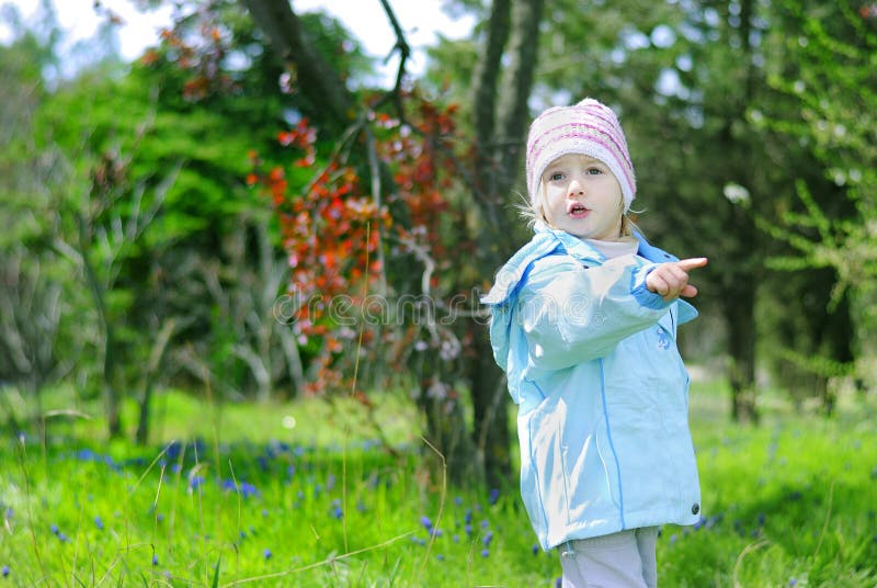 Bambina su erba verde in primavera nel parco per una passeggiata immagine stock Bambina su erba verde in primavera nel parco per una passeggiata immagine stock