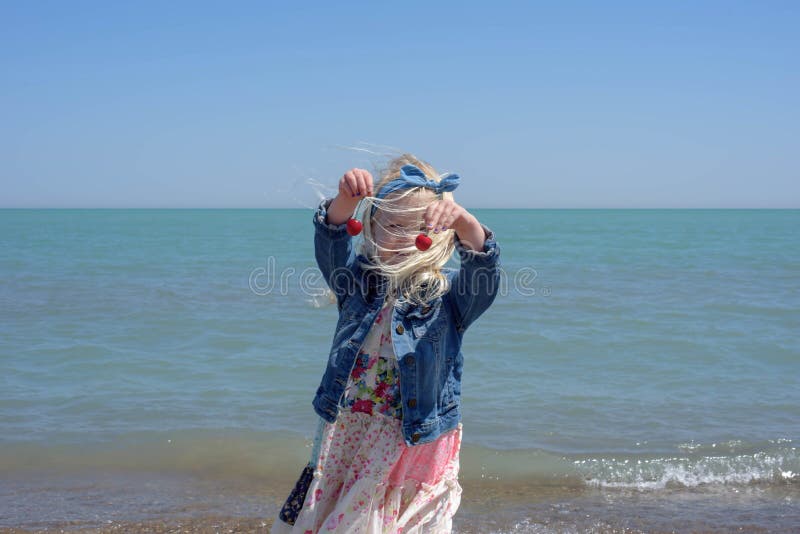 Bambina sveglia alla spiaggia un giorno ventoso fotografia stock Bambina sveglia alla spiaggia un giorno ventoso fotografia stock