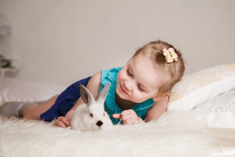 Bambina sveglia che gioca con i conigli bianchi immagini stock libere da diritti Bambina sveglia che gioca con i conigli bianchi immagini stock libere da diritti