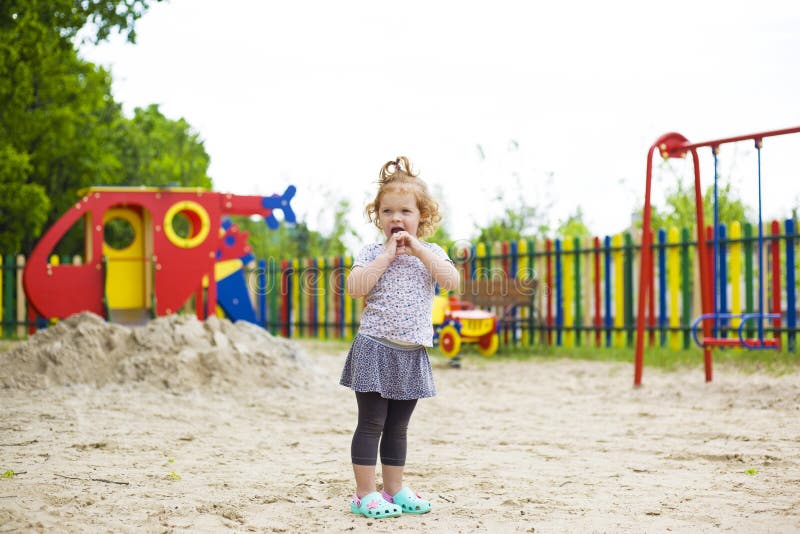 Bambina sveglia con capelli rossi che stanno in mezzo al campo da giuoco fotografie stock Bambina sveglia con capelli rossi che stanno in mezzo al campo da giuoco fotografie stock