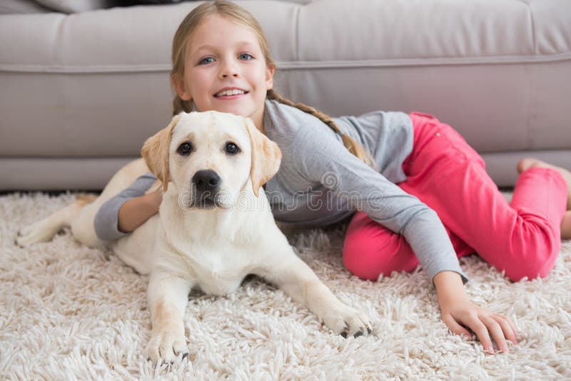 Bambina sveglia con il suo cucciolo sullo strato immagini stock Bambina sveglia con il suo cucciolo sullo strato immagini stock