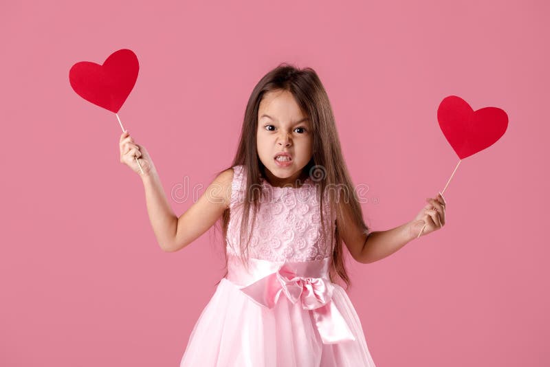 Bambina sveglia in un vestito rosa che tiene un cuore di carta immagini stock libere da diritti Bambina sveglia in un vestito rosa che tiene un cuore di carta immagini stock libere da diritti