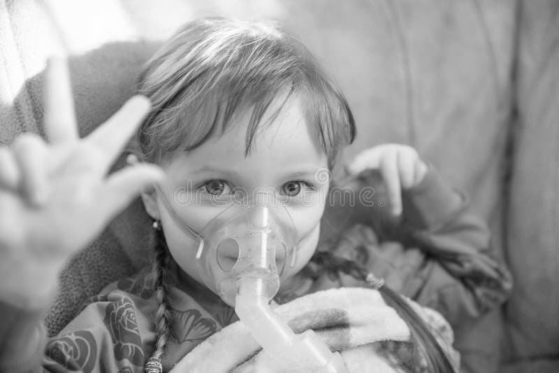 Bambina in una maschera, vie respiratorie di trattamenti con un nebulizzatore a casa, incolore