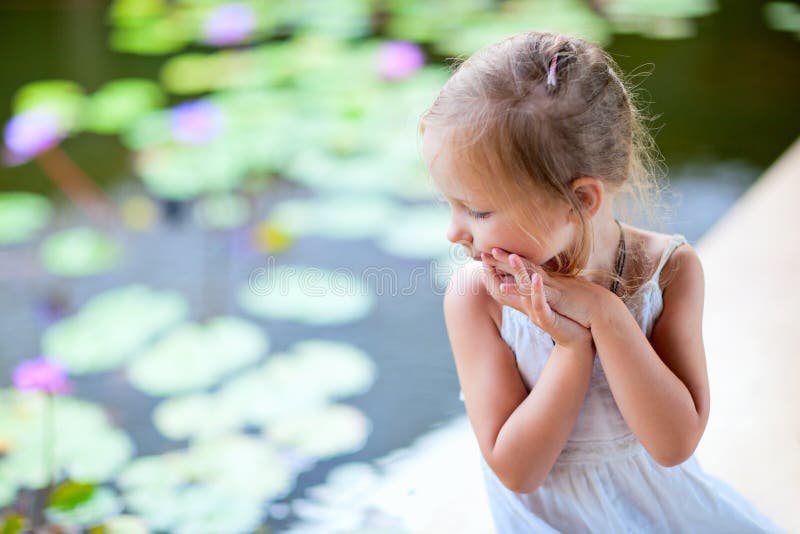 Bambina vicino allo stagno del giglio fotografia stock Bambina vicino allo stagno del giglio fotografia stock