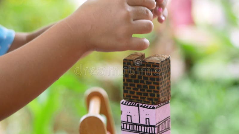 Bambine di conifere carine che giocano a colori in blocchi di legno nel cortile di casa. giocare è imparare per i bambini. scuola video d archivio