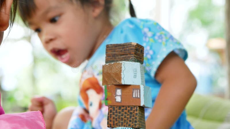 Bambine di conifere carine che giocano a colori in blocchi di legno nel cortile di casa. giocare è imparare per i bambini. scuola archivi video