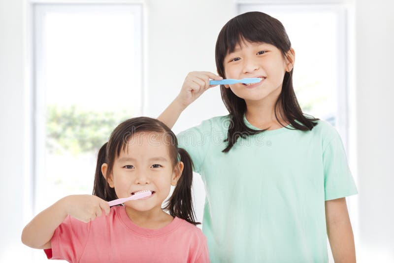Bambine felici che puliscono i suoi denti fotografia stock