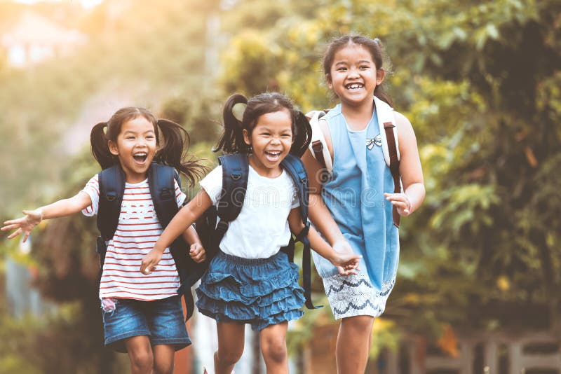Bambini asiatici dell'allievo con funzionamento dello zaino fotografia stock Bambini asiatici dell'allievo con funzionamento dello zaino fotografia stock