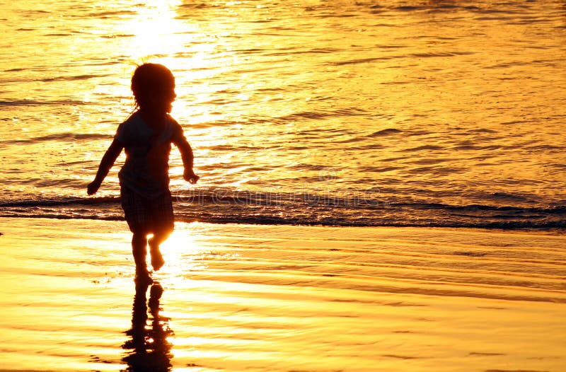 Children playing at the beach in Bali, Indonesia during a golden sunset. Ocean like gold. The sand and the water look like they were made of gold. Unique moment captured by the camera. Children playing at the beach in Bali, Indonesia during a golden sunset. Ocean like gold. The sand and the water look like they were made of gold. Unique moment captured by the camera.