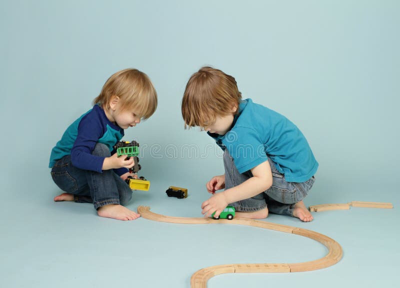 Bambini che giocano con i treni del giocattolo immagini stock Bambini che giocano con i treni del giocattolo immagini stock
