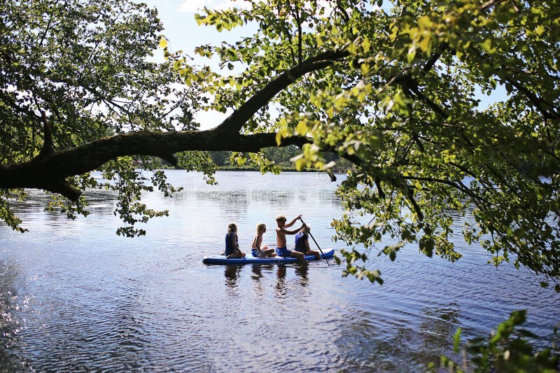 Bambini che giocano a paddle board in un lago il giorno dell'estate fotografia stock libera da diritti